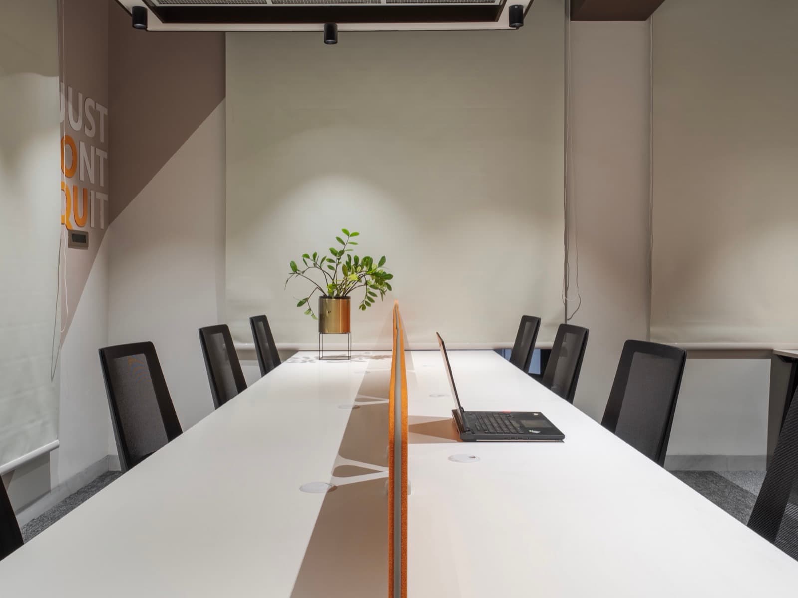 Long shared desk beneath the Just Dont Quit mural in the 12 seater lake view office at Fliqzo