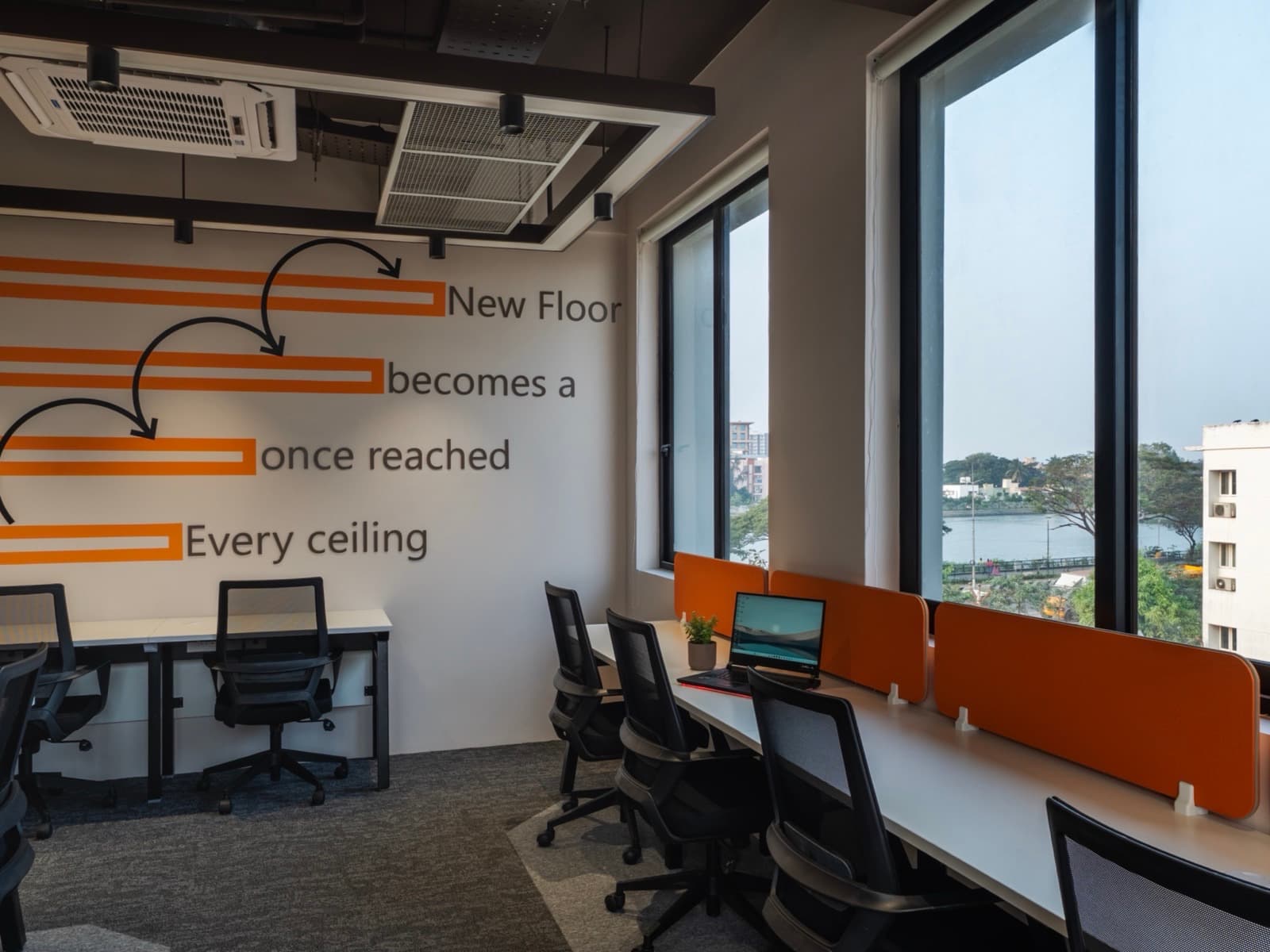 Every Ceiling Once Reached Becomes A New Floor mural beside lake-view windows in the 16 seater private office at Fliqzo