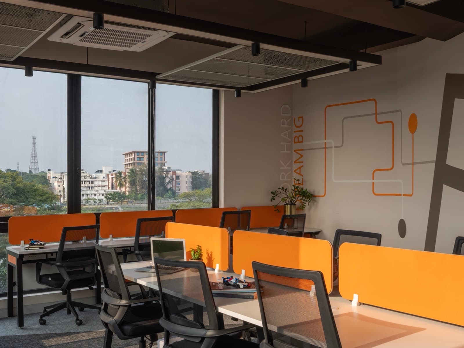 Work Hard Dream Big wall beside sunlit desk pods in the 16 seater lake view private office at Fliqzo
