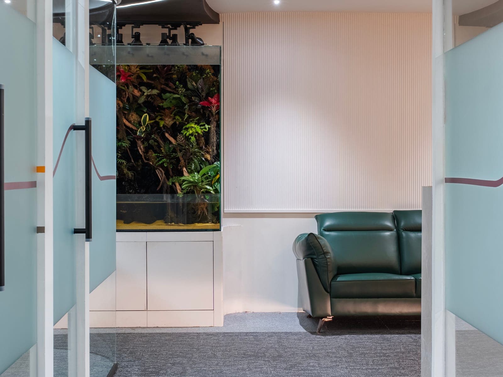 Lounge with living paludarium and green leather sofa outside the 5 seater private office at Fliqzo Coimbatore