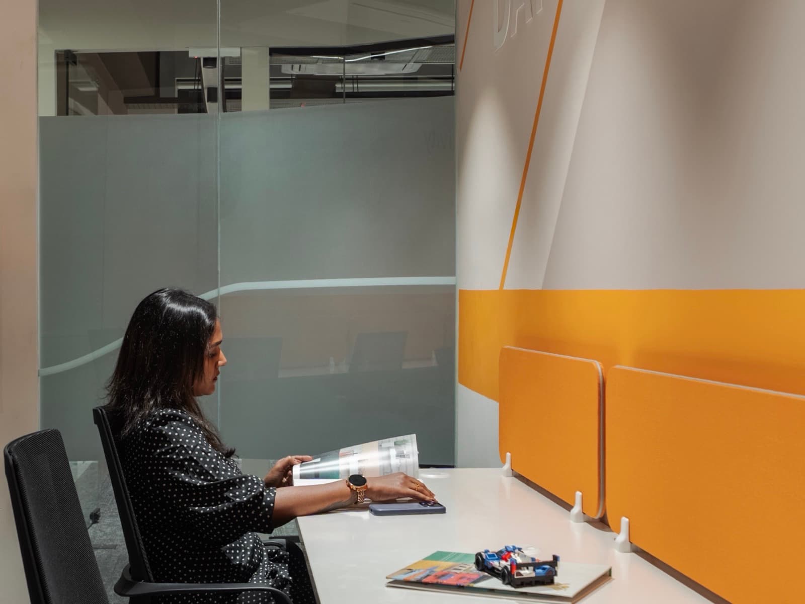 Member reading a magazine beside the Challenge Yourself Every Day wall in the 8 seater lake view office at Fliqzo