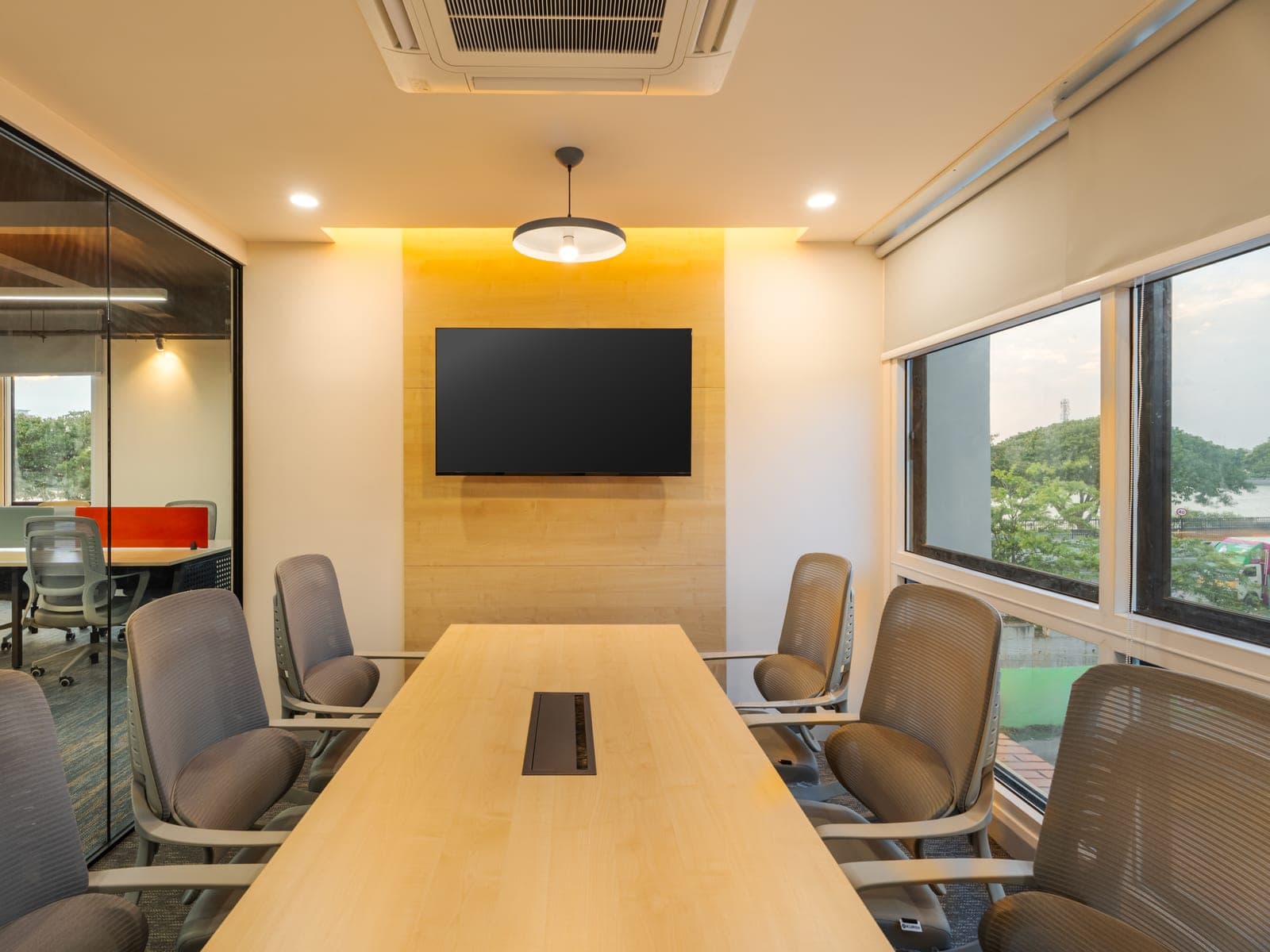 Six seater conference room with wall-mounted display and lake-view windows in the Exzeo managed office by Fliqzo