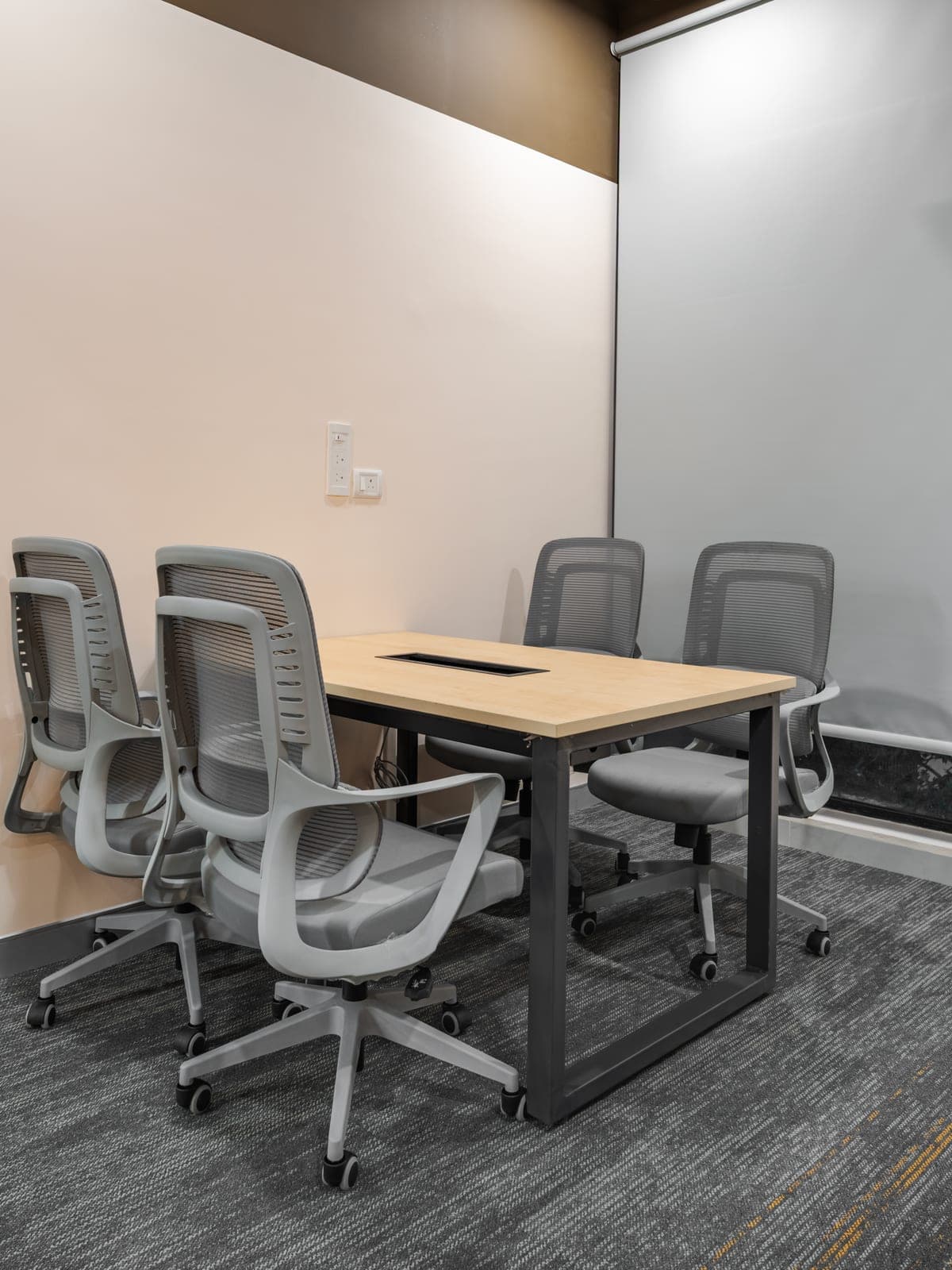 Four seater focus room behind acoustic glass in the Exzeo managed office built by Fliqzo, Coimbatore