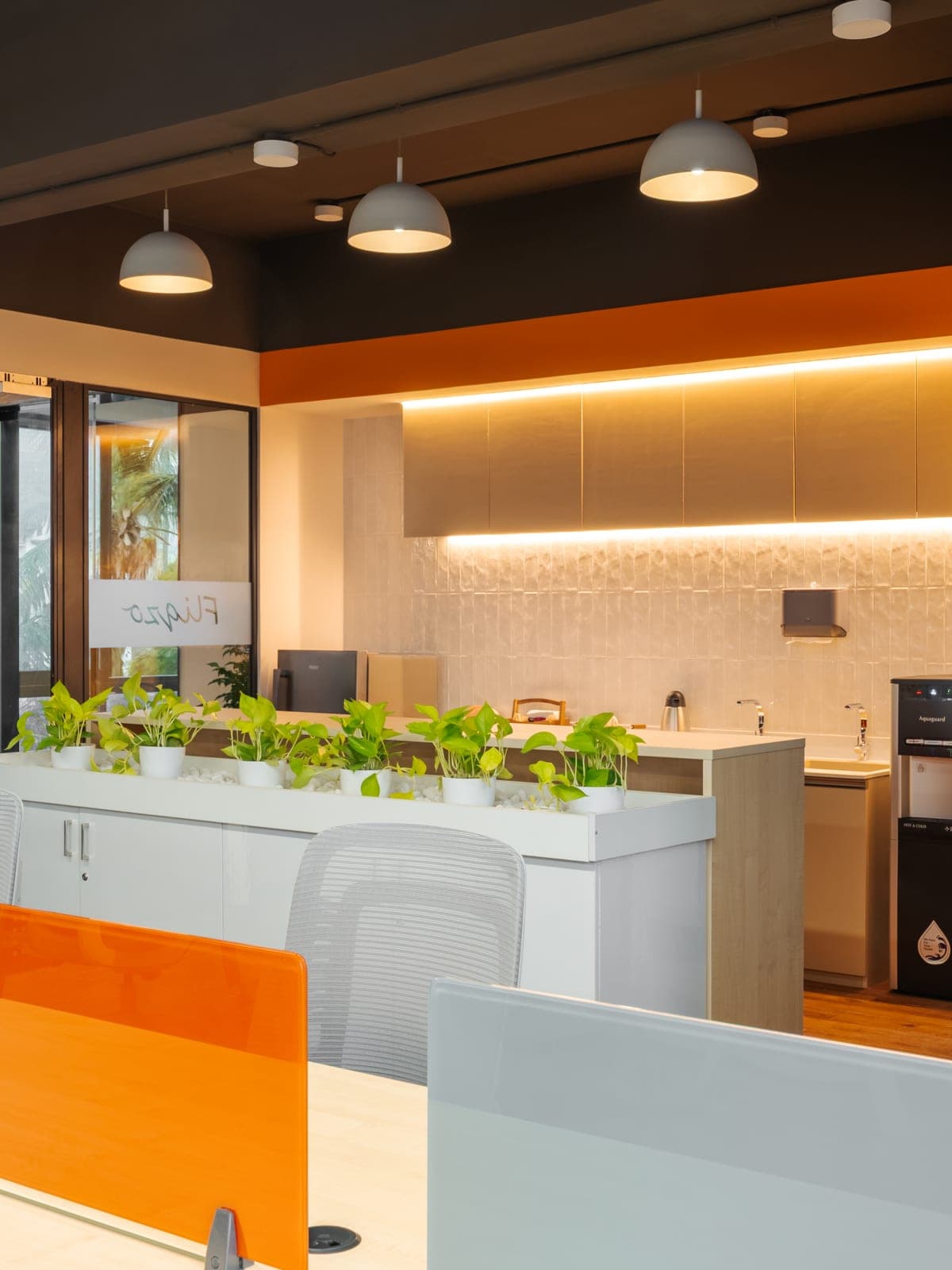 Pantry with under-cabinet lighting and potted plants inside the Exzeo managed office by Fliqzo, Coimbatore