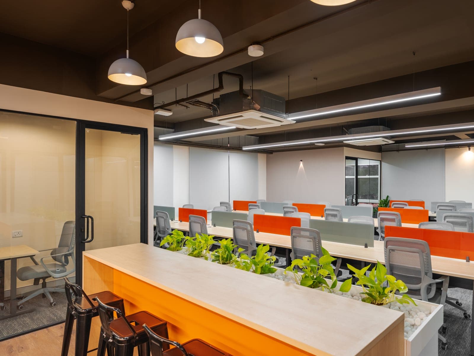 Live plants along the planter bar between the open workstations of the Exzeo managed office by Fliqzo