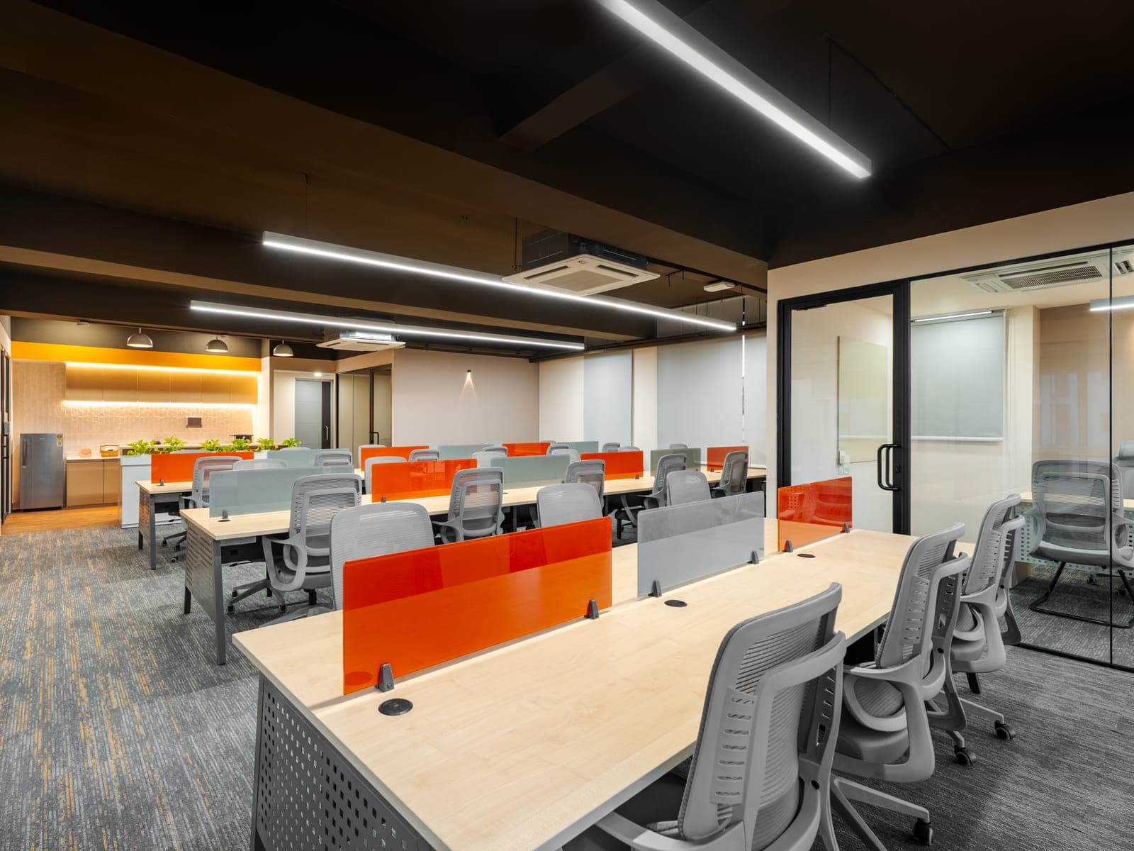 Thirty open workstations with orange glass dividers across the Exzeo managed office floor built by Fliqzo, Coimbatore