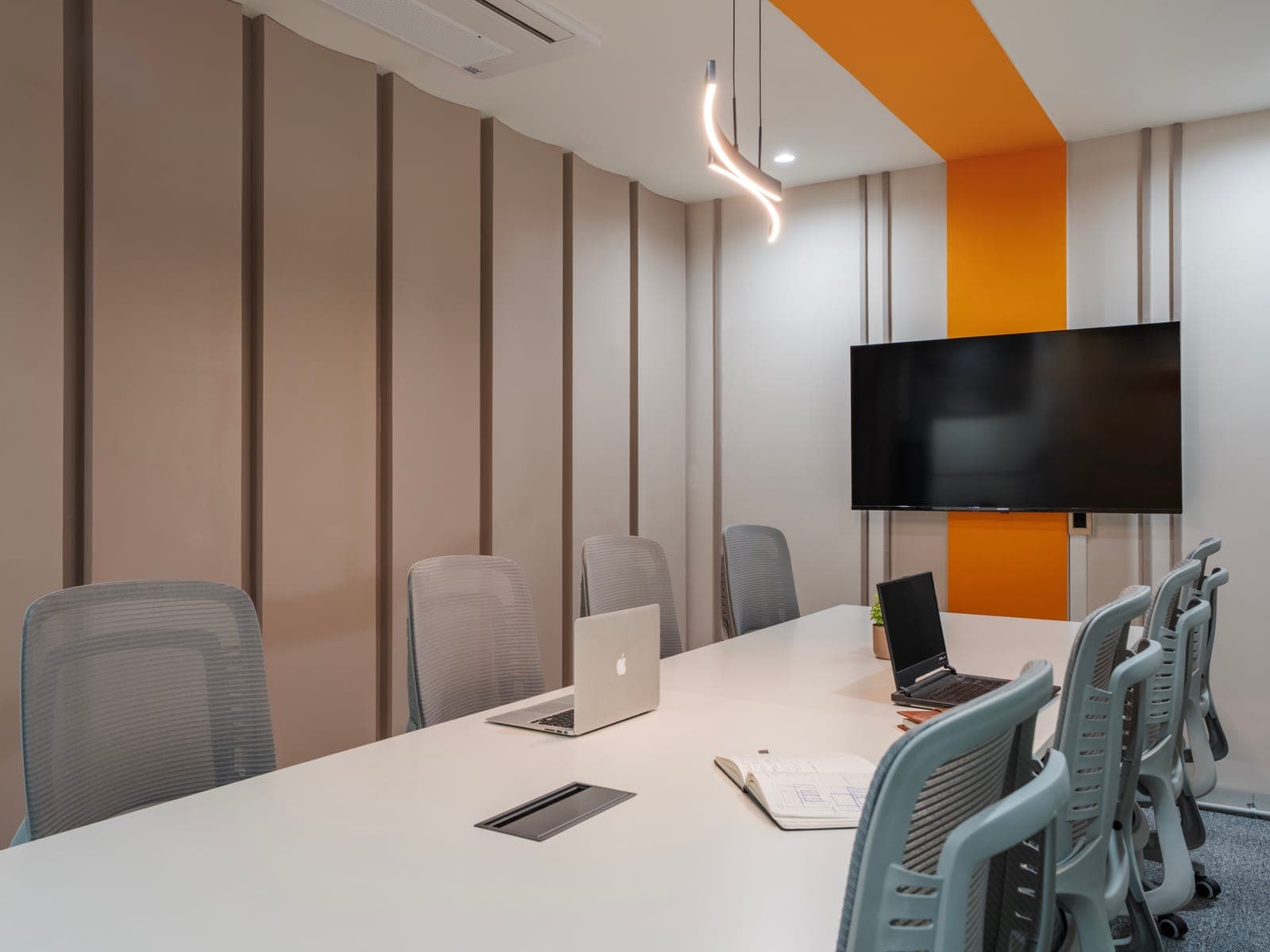 Sculpted panelled wall and designer pendant light across the eight-seat meeting room at Fliqzo