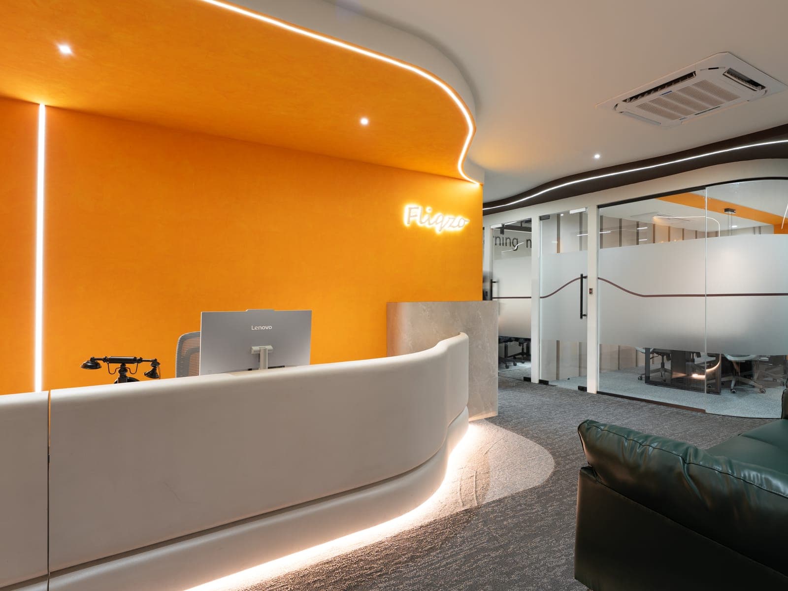 Fliqzo reception where meeting-room guests are welcomed, with backlit logo and marble counter, Coimbatore